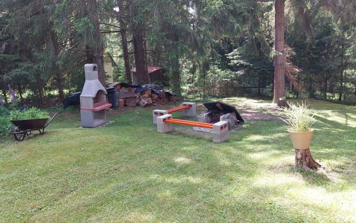 Pohľad od schodov chaty na gril ,ohnisko a lavičky